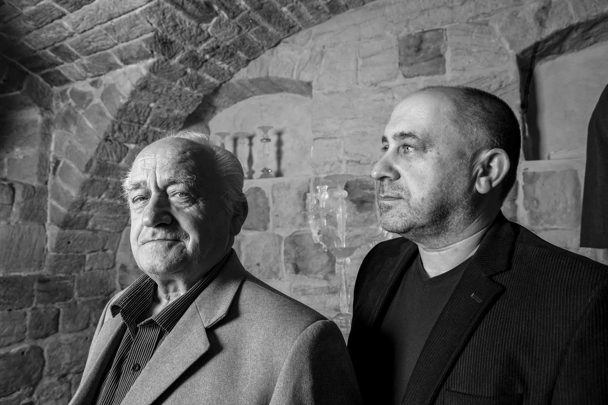 Jaroslav Bejvl Sr. and Jr. side by side in a vaulted stone cellar